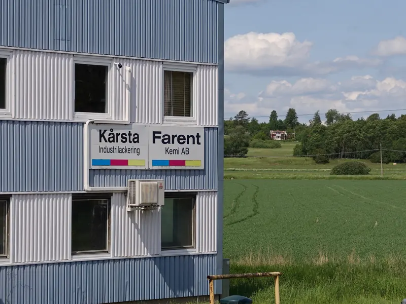 Skylten Kårsta Industrilackering på husets gavel med åkern i bakgrunden